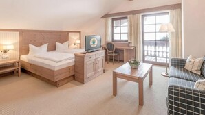 Une chambre d’hôtel avec un lit, un bureau, une chaise, un canapé et un lustre.