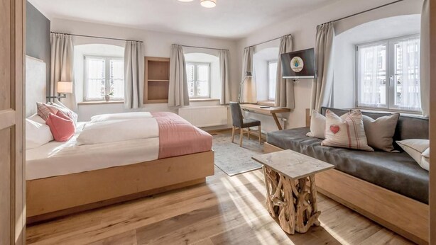 Une chambre à coucher moderne et bien éclairée, avec un grand lit, un bureau et un canapé.