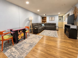 A living room with a sectional sofa, a small table with chairs, a television, and a fireplace.