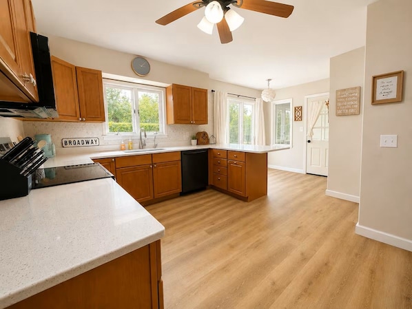 A kitchen with wooden cabinets, a countertop, and a ceiling fan.