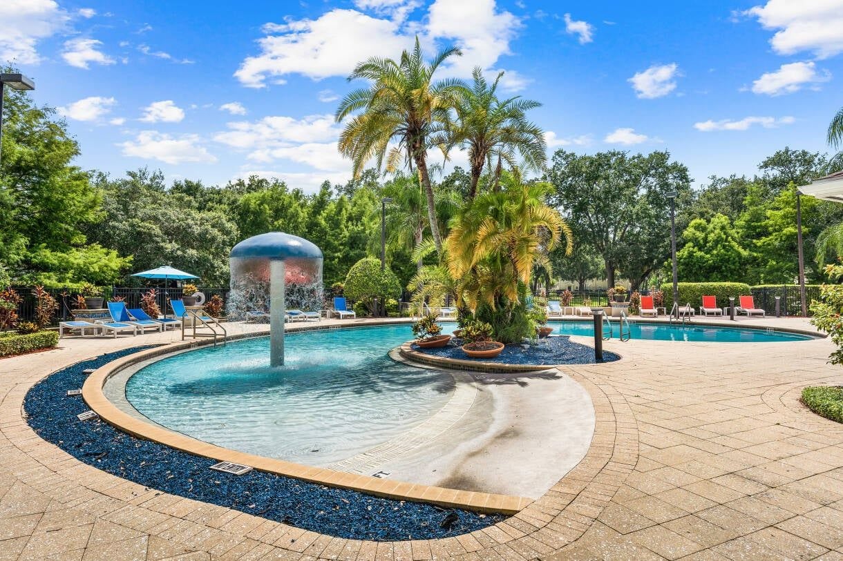 A pool area with lounge chairs and palm trees.