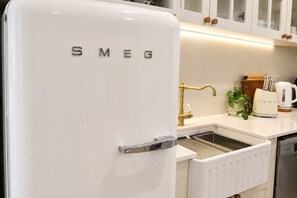 A kitchen with a white Smeg refrigerator, a gold faucet, and a white kettle on the counter. - Buddina Boutique Coastal Studio on the Waterfront (Buddina)