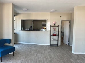 A reception area with a counter, a blue chair, and a shelf with decorative items. - Your Place to stay! Big SEC Clash 1 Bedroom King Bed. Dreamland Inn in Senatobia (Senatobia)