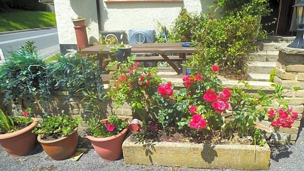 A garden with potted plants and a wooden bench. - Englands Rose Pub (Thame)