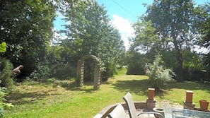 A garden with a stone archway, a table with chairs, and a grassy area. - Englands Rose Pub (Thame)