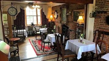 Un comedor con mesas y sillas, una pared de ladrillo y un reloj.