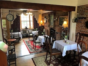 A dining area with tables and chairs, a brick wall, and a clock. - Englands Rose Pub (Thame)