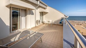 A balcony with a view of the beach, outdoor seating, and an air conditioning unit. - Parigi (Caorle)