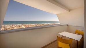 A balcony with a view of a beach, a small table, and two chairs. - Parigi (Caorle)