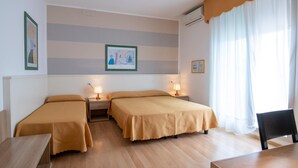 A hotel room with two single beds, a desk, and a chair. - Parigi (Caorle)