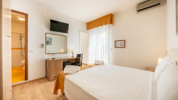 A hotel room with a bed, a desk, a chair, a shower, and a television. - Parigi (Caorle)