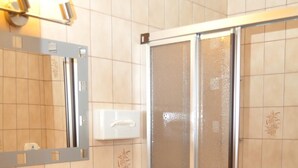A bathroom with a sink, mirror, towel rack, and a glass-enclosed shower. - Alemannenhof Engel (Rickenbach)