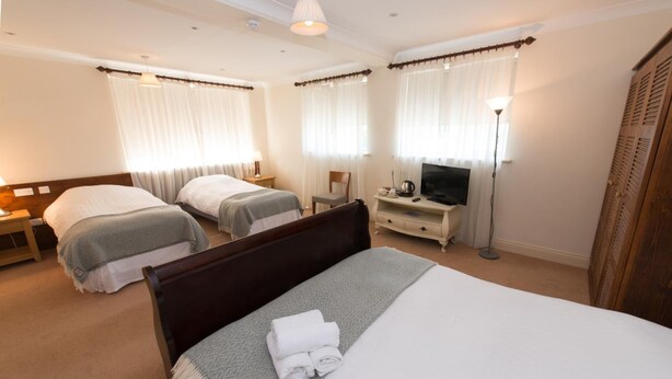 Une chambre d’hôtel avec deux lits simples, un grand lit, une télévision, un bureau et une armoire.