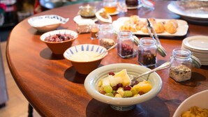 Une table de buffet proposant divers plats, notamment un saladier de salade de fruits, une assiette de pâtisseries et plusieurs petits pots de condiments.