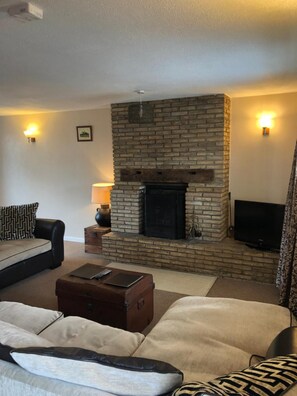 Una sala de estar con chimenea de ladrillo, un sofá, una mesa de centro y un televisor.