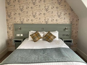 A bedroom with a bed, two nightstands, and a patterned wallpaper. - Tullie Inn (Alexandria)