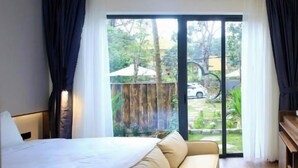 A hotel room with a bed, a sofa, a desk, and a view of the outdoors. - DD Hospitality - Mi Amor Da Lat (Xuan Huong - Da Lat)