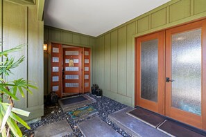 A traditional wooden door with a glass panel, a stone pathway leading to the entrance, and a doormat with a turtle design. - 🏖️Starry Nights | 2 King Ensuites, Central AC & Sleeps 10 (Waikoloa)