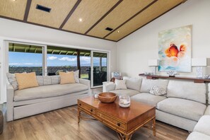 A spacious living room with a large window, a wooden coffee table, and two sofas. - 🏖️Starry Nights | 2 King Ensuites, Central AC & Sleeps 10 (Waikoloa)