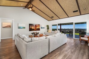 Ein geräumiges Wohnzimmer mit einem großen Ecksofa, einem Essbereich und Blick ins Freie.