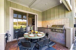 An outdoor dining area with a round table set for four, surrounded by chairs. - 🏖️Two King Ensuite Bedrooms + Pools & Hot Tubs (Kamuela)