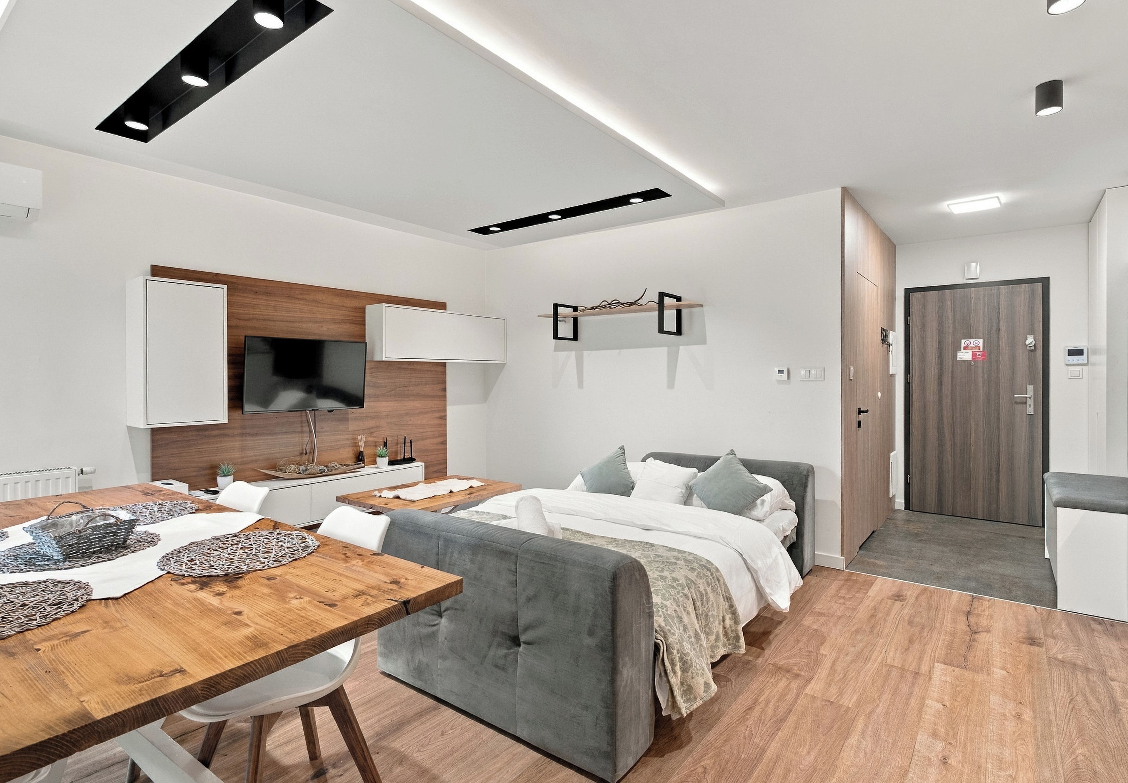 Ein modernes, helles Zimmer mit Essbereich, einer Couch und einem Bett.