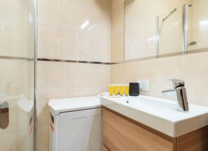 Ein modernes Badezimmer mit einem weißen Waschbecken, einem Spiegel und einer Duschkabine aus Glas.