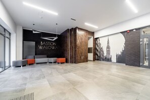 Eine moderne Lobby mit einer Rezeption, einer Sitzgelegenheit und einem Stadtbild-Mural.