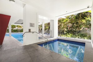 A swimming pool with a tiled edge, a metal handrail, and a sign with spa rules. - 2 Bedroom Hideaway (Surfers Paradise)