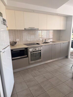 Una cocina moderna con electrodomésticos de acero inoxidable, salpicadero de azulejos y armarios de tonos claros.