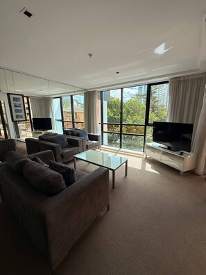 A modern living room with a sofa, coffee table, and a flat-screen TV. - 2 Bedroom Hideaway (Surfers Paradise)