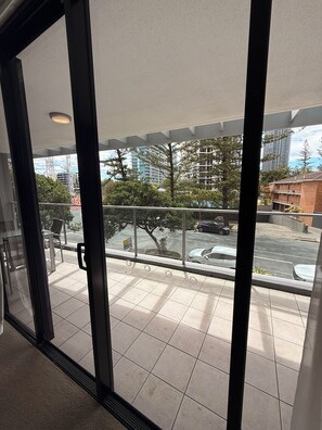 A view from a balcony with a glass door, overlooking a parking area and buildings. - 2 Bedroom Hideaway (Surfers Paradise)
