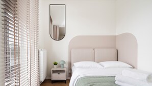A bedroom with a bed, bedside table, lamp, and a window with blinds. - Łódź Fabryczna Signature Apartment (Łódź)