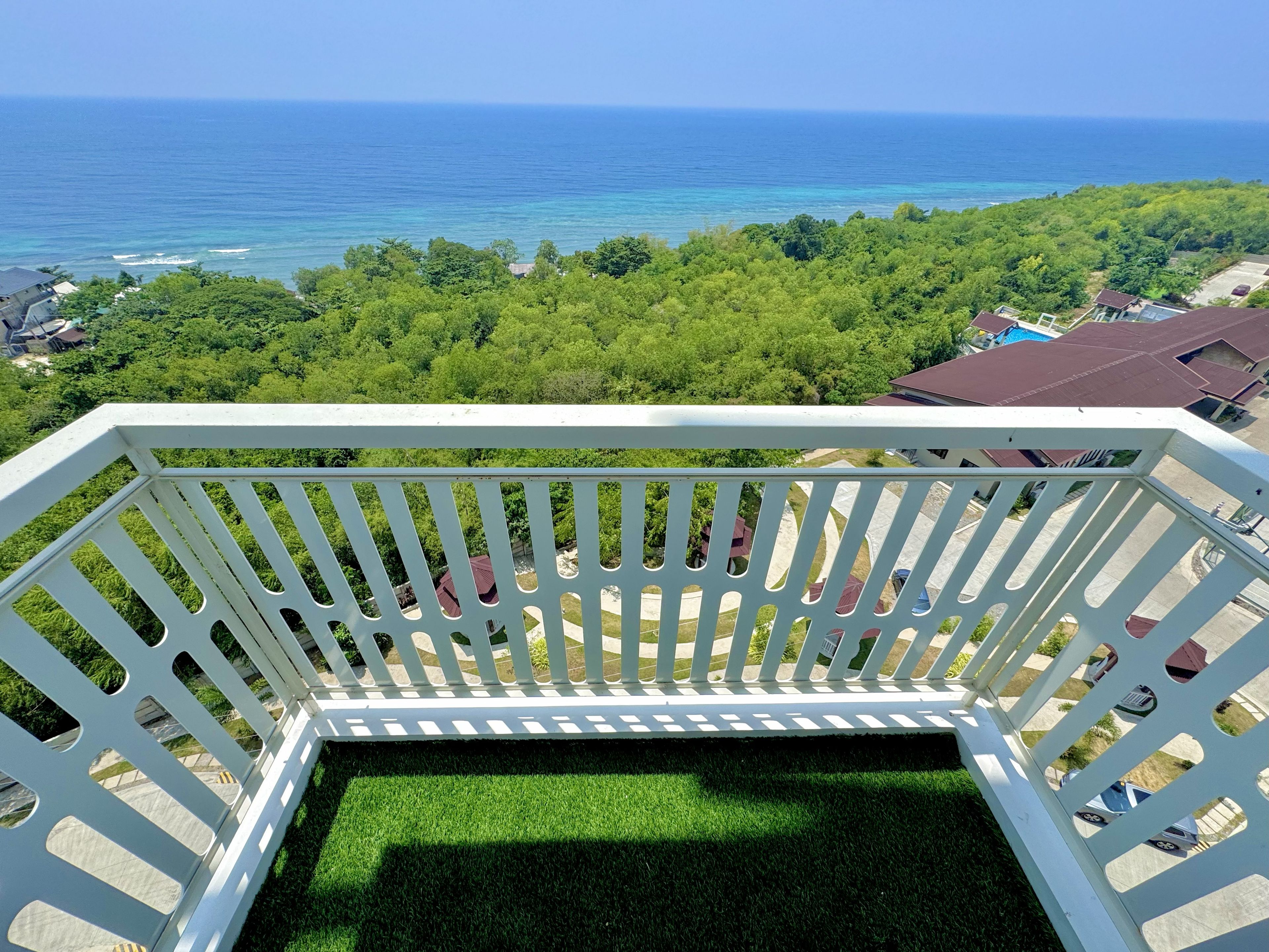A balcony with a view of the ocean and a lush green landscape.