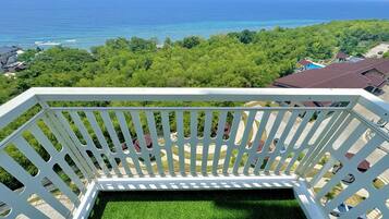 A balcony with a view of the ocean and a lush green landscape.