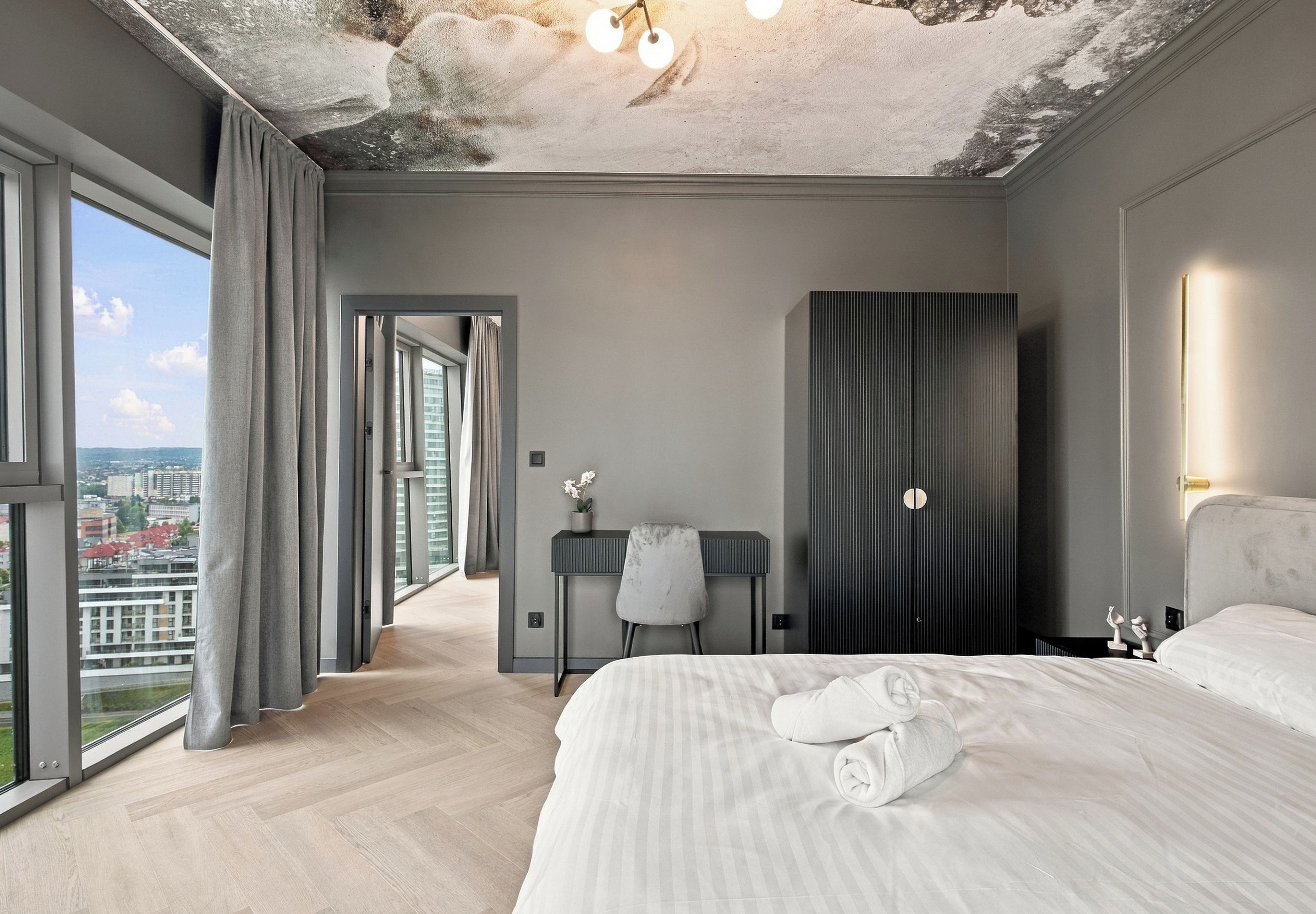 Ein modernes Hotelzimmer mit einem großen Bett, einem Schreibtisch und Blick auf die Stadt.