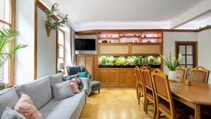 Ein Wohnzimmer mit einer Couch, einem Esstisch mit Stühlen, einem Fernseher und einem Aquarium.