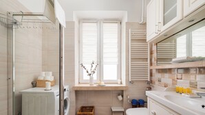 Ein modernes Badezimmer mit einer Bosch Waschmaschine, einer Toilette, einem Korbwäscheschrank und einem Fenster mit Jalousien.