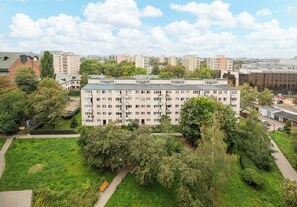 A multi-story residential building with a flat roof, surrounded by greenery and other buildings. - Metro Wierzbno Homely Apartment (Warszawa)