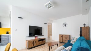 Ein modernes Wohnzimmer mit einem Flachbildfernseher, Holzmöbeln und einem blauen Sofa.
