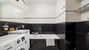 Ein modernes Badezimmer mit Waschmaschine, Badewanne und Toilette.