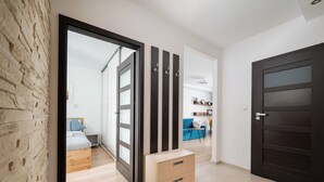 Ein modernes Interieur mit Holzboden, einer dunklen Tür und einem Zimmer mit Bett und blauem Sofa.