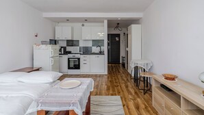 A modern hotel room with a kitchenette, a dining area, and a bed. - Piastów Standard Studio (Katowice)