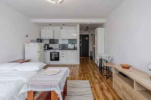 Habitació d'hotel moderna amb cuineta, zona de menjador i un llit.