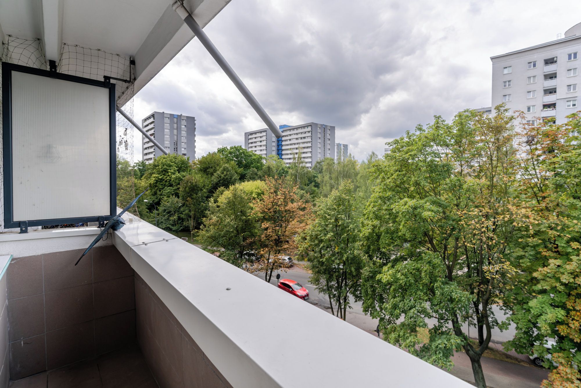 Ein Balkon mit Blick auf eine Skyline, darunter hohe Gebäude und Bäume.