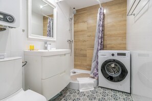 Bany compacte amb vàter, rentatòries, dutxa i rentamàquines.