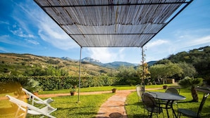Un pati amb una pèrgola, mobiliari d'exterior i vista a un paisatge de muntanya.