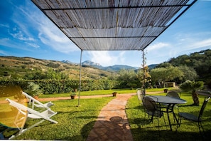 A patio with a pergola, outdoor seating, and a view of a mountainous landscape. - C/da Pozzetti Apartment (Lascari)