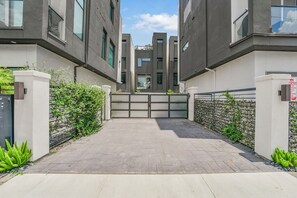 A modern building with a gated entrance, paved pathway, and greenery. - Luxury Retreat Near Memorial & Heights. Sleeps 8 with Wellness Studio (Houston)