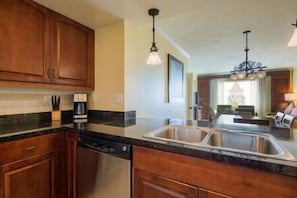 A kitchen with wooden cabinets, a stainless steel sink, and a dishwasher.